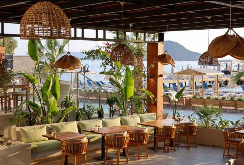 Un restaurante con mesas y sillas y vista al agua. en Sundance Suites Hotel, en Turgutreis
