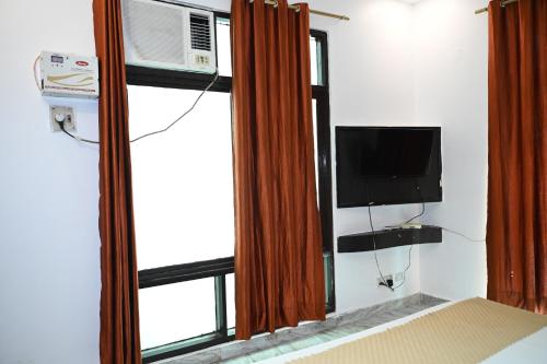 a room with a tv and a window with a television at Happpy Stay in Lucknow