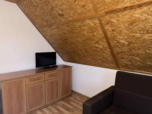 - un salon avec un canapé et une télévision sur une armoire en bois dans l'établissement U Magdy nad Tałtami II, à Tałty