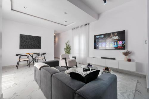 a living room with a couch and a tv on a wall at Serviced 2bed Home in Lekki in Ikate