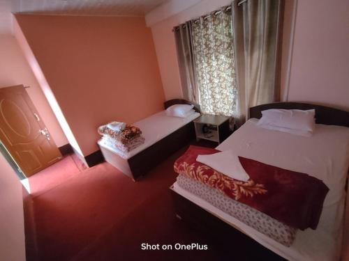 a small bedroom with two beds and a window at Jamuna Homestay in Kalimpong