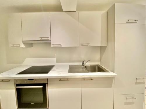 a white kitchen with a sink and white cabinets at 2 room apartment, free parking and wifi in Geneva