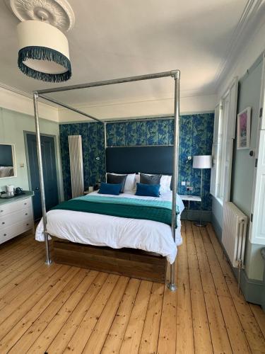 a bedroom with a canopy bed with blue walls at Hopewell - Unique Rooms in the heart of Cliftonville in Margate
