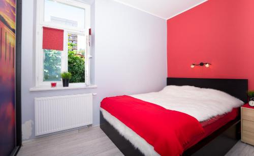 a red bedroom with a bed and a window at Apartament Sopot Kamienny Potok in Sopot