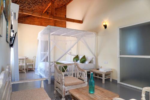 a bedroom with a canopy bed and a table and chairs at Exotica Bungalows in Hikkaduwa