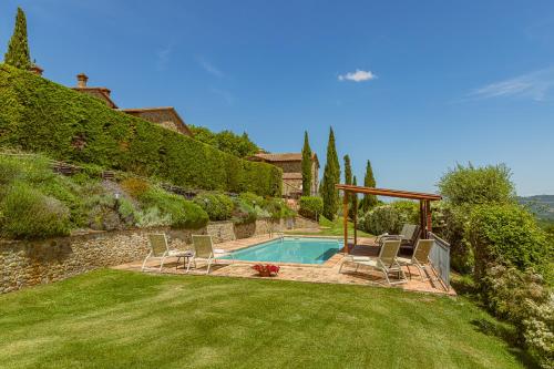 a swimming pool in a yard with chairs in the grass at Casa Baiocco in Città della Pieve