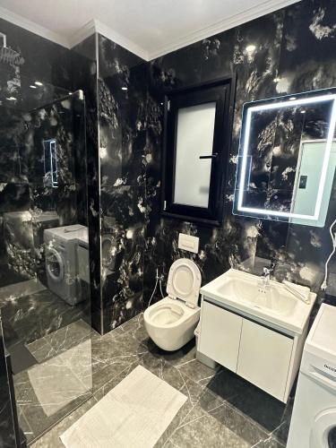 a black and white bathroom with a toilet and a sink at LiEl Holiday in Vlorë