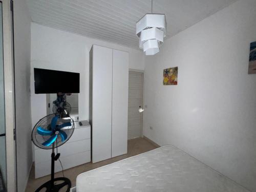 a white bedroom with a bed and a television at rupea breeze home in Tropea