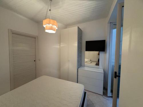 a white room with a bed and a tv and a table at rupea breeze home in Tropea