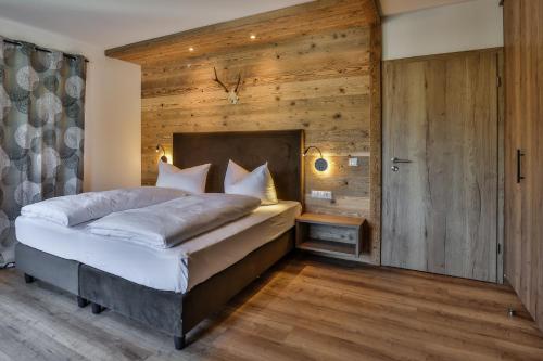 a bedroom with a large bed and wooden walls at Ferienwohnungen - Alpenhotel Fischer 4 Sterne - Adults Only in Berchtesgaden