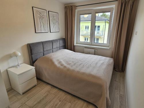 Un dormitorio pequeño con una cama y una ventana. en Apartament z widokiem na las, en Ustka