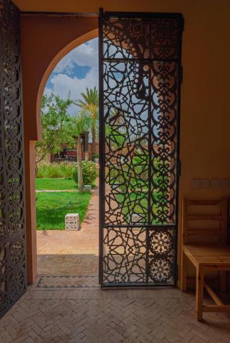 an open gate with a view of a garden at Dar Lily, villa familiale avec piscine et services in Skoura