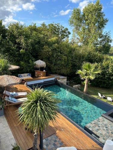 - une piscine dans un jardin avec une terrasse en bois dans l'établissement La chambre l'Eucalyptus, à Saint-Laurent-du-Bois