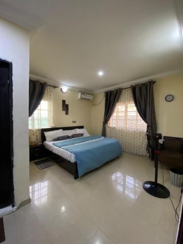 a bedroom with a blue bed and some windows at Realms Apartment in Abuja