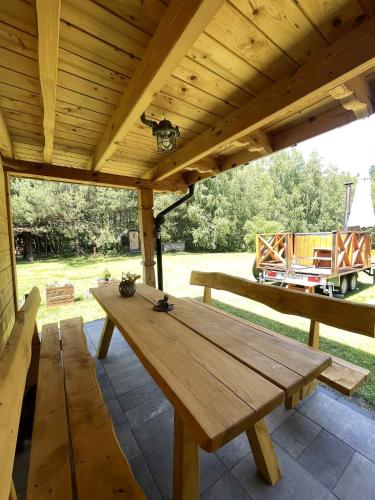 a wooden picnic table under a wooden roof on a patio at Chatka przy lesie Roztocze Szewnia Dolna 74 22-442 in Szewnia