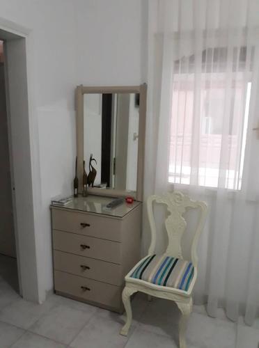 a dresser with a mirror and a chair in a room at Anna-Maria in Nea Kalikratia