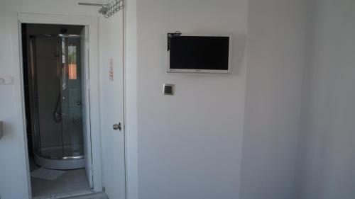 a bathroom with a shower and a television on the wall at Hotel Marine in Ayvalık