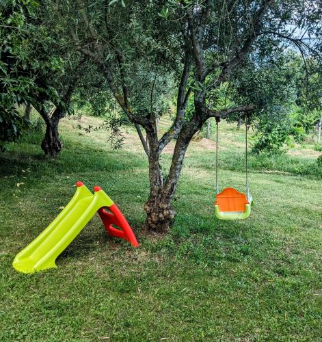 two childrens play equipment in the grass next to a tree at B&B Casal Cominium in San Donato Val di Comino