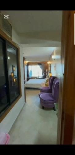 マリーにあるKashmir Point View Apartmentの紫色の椅子2脚とベッドのあるリビングルーム