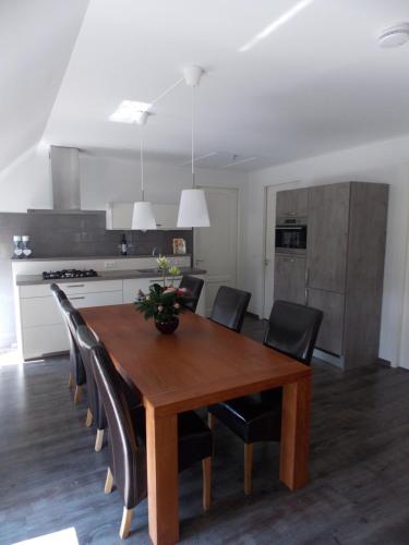 a kitchen with a wooden table and black chairs at Bed and breakfast de Boerderij in Albergen