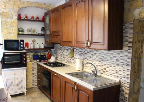a kitchen with wooden cabinets and a sink at La Rosa dei Venti in Alghero