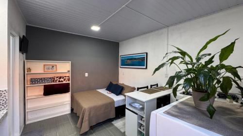 ein Schlafzimmer mit einem Bett und einer Topfpflanze in der Unterkunft Studio Beira Mar in Imbituba