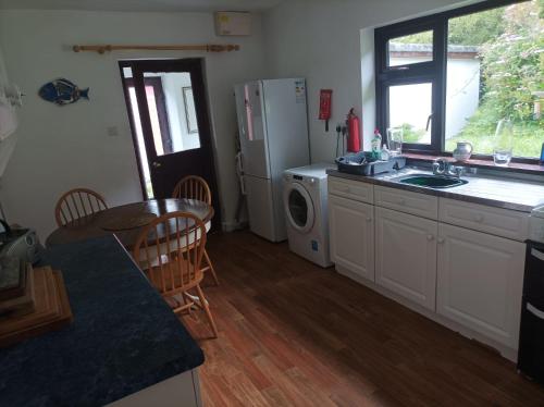 a kitchen with a sink and a refrigerator and a table at Tievemore - Connemara Bayfront Retreat in Moyard