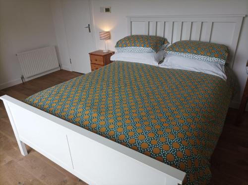 a bedroom with a large white bed with a green comforter at Tievemore - Connemara Bayfront Retreat in Moyard
