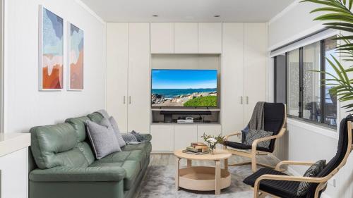 a living room with a couch and a tv at Sandy Point Escape in Corlette