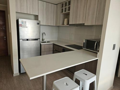 a kitchen with a refrigerator and a counter with two stools at Premium Executive Apartment en Ñuñoa in Santiago