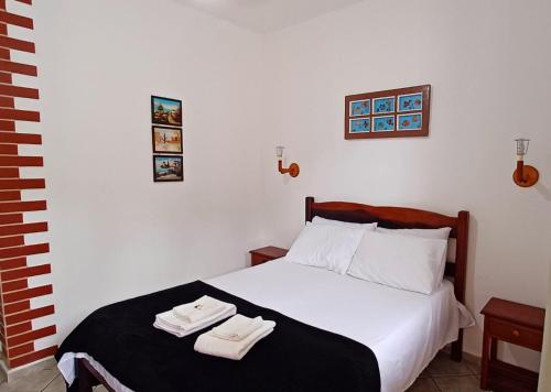 a bedroom with a bed with two towels on it at Pousada Vila das Artes in Paraty