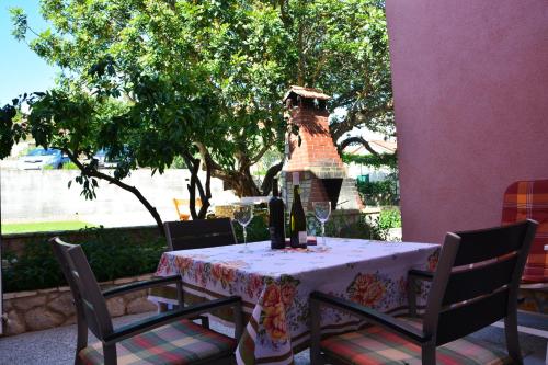a table with chairs and a table with wine glasses at Apartments Ena in Vrboska