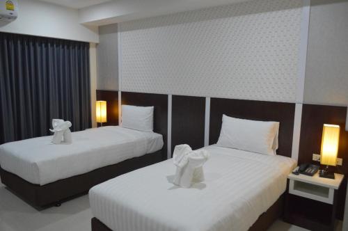 two beds in a hotel room with towels on them at Som-O House Hotel in Nakhon Ratchasima