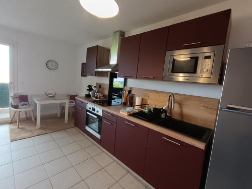 La cuisine est équipée de placards bruns, d'un évier et d'un four micro-ondes. dans l'établissement Charmant appart ,Proche de la plage, à San-Martino-di-Lota