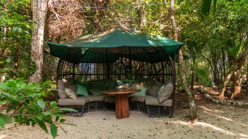 a gazebo with a couch and a table under an umbrella at Apartamento Flamingo - Santuario Apartments in Chemuyil