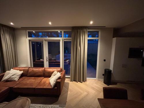 a living room with a couch and a large window at Bos chalet Hellendoorn met Hottub in Haarle