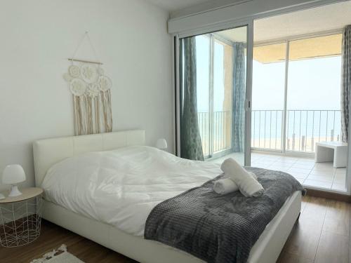 a white bedroom with a bed with a teddy bear on it at Le panoramique du Barcares in Le Barcarès
