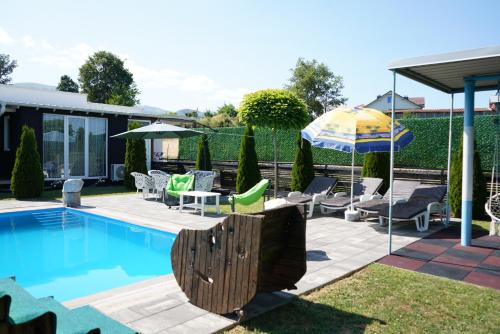 a swimming pool with chairs and an umbrella at Villa Hoti Your Private Getaway in Mitrovicë