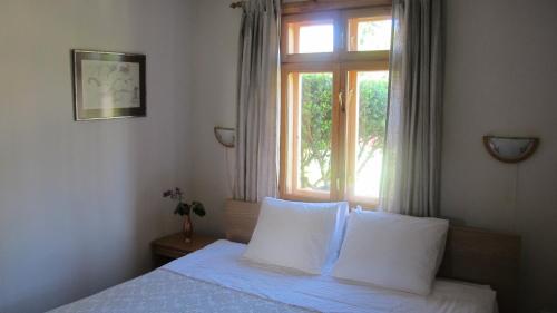 a bedroom with a bed with white sheets and a window at Smilčių namelis in Palanga