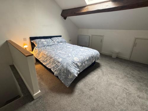 a bedroom with a bed with a blue comforter at Sowerby apartments in Sowerby Bridge