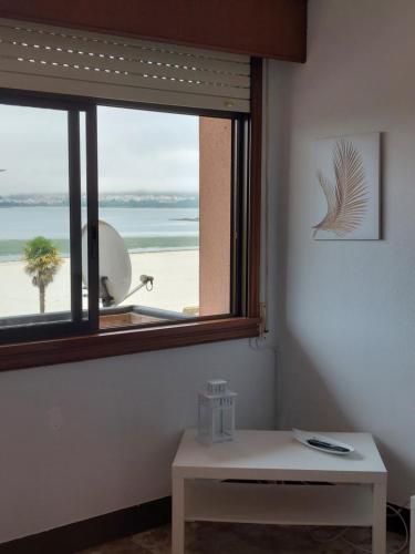 a window with a view of a beach and a table at Piso 4 dormitorios playa sada in Sada
