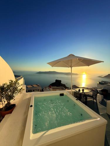 a swimming pool with an umbrella and a table at Sunset Caldera Seaview Houses in Imerovigli