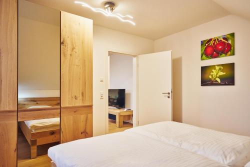 a bedroom with a white bed and a desk at Müller s Ferienhäusle UG in Vogtsburg