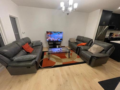 a living room with two couches and a flat screen tv at Bedroom private Bathroom in Upland in Edmonton