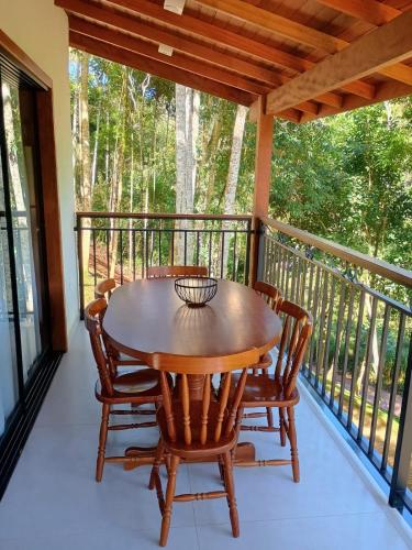 a porch with a wooden table and chairs on a balcony at Lindo Chalé a 7 minutos do Centro in Domingos Martins