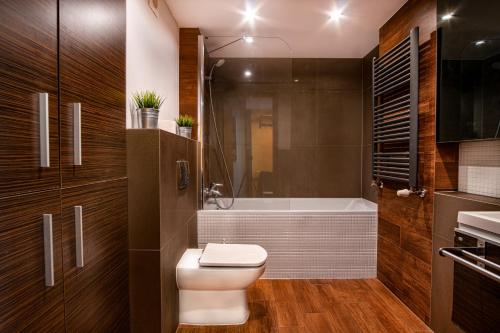a bathroom with a toilet and a bath tub at Dream Aparts - Lofty Scheiblera in Łódź