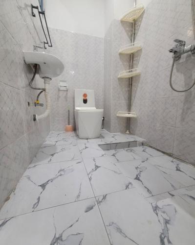a bathroom with a white marble floor and a toilet at Appartement Amani in Kinshasa