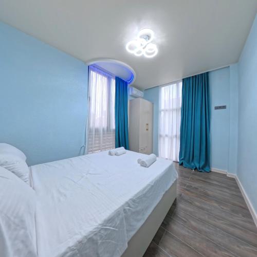 a bedroom with a white bed with blue walls and windows at Premium apartment in Ureki