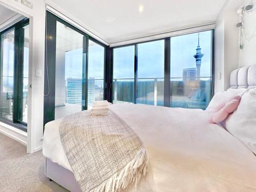 a bedroom with a large white bed and large windows at High-Floor 2BR Apt Sky Tower view AC Pool Gym in Auckland