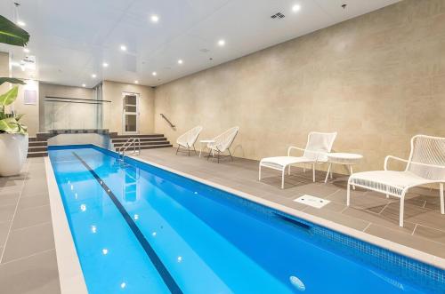 a swimming pool with white chairs and a swimming pool at High-Floor 2BR Apt Sky Tower view AC Pool Gym in Auckland